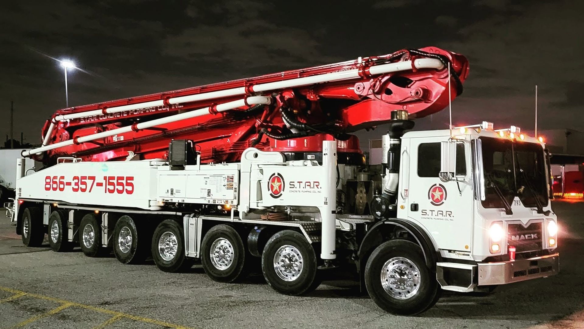 S.T.A.R. Concrete Pumping red and white Mack boom pump truck lit up at night